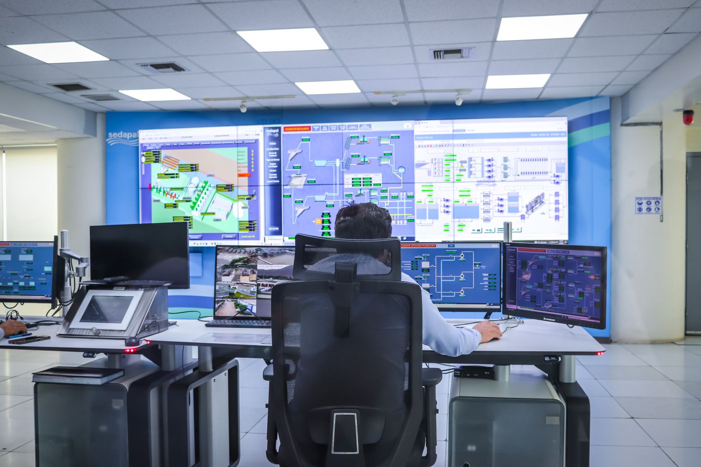 An operator at a desk of monitors in a control room